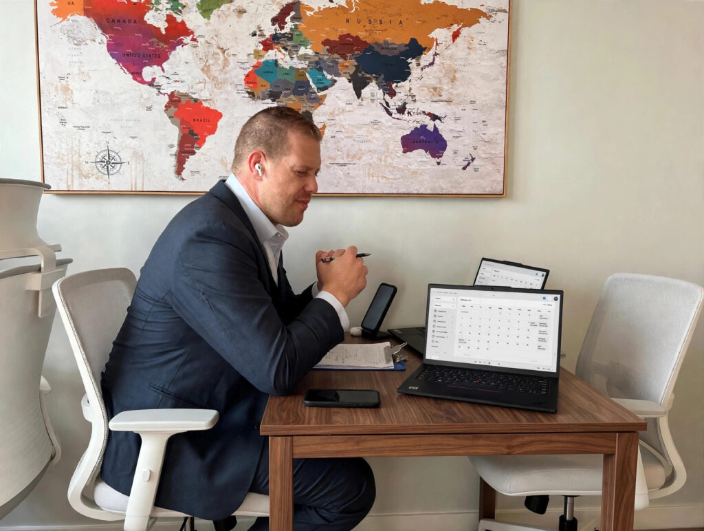 Man holding pen beside scheduling laptop